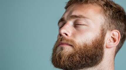 Obraz premium Man with beard, relaxed pose, light blue background. Stock Photo