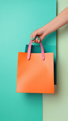 A woman's elegant hand holds vibrant shopping bags in bold orange, teal, and fuchsia. The colorful bags exude a sense of modern fashion and consumer appeal, perfect for style enthusiasts.