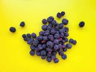 Dried portion of yummy blueberries on a yellow background.