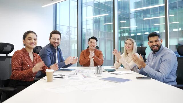 Group of business corporate people applauding look at camera sitting in office boardroom celebrate success. Happy satisfied successful professional diverse team business colleagues rejoice achievement