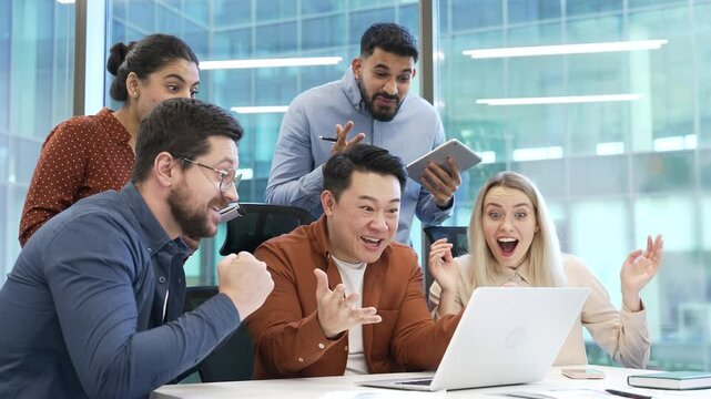 Happy excited team business people celebrate success and achievement look at laptop computer sitting in modern office. Group of joyful professionals colleagues received great news successful results