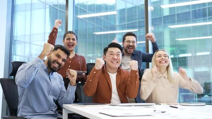 Group of happy excited business people watching sports match or cheering for bids at auction on TV sitting in modern office. Joyful colleagues celebrating success showing excitement and achievement