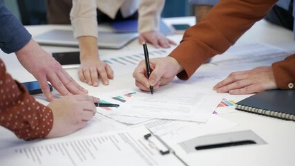 Close up of group of business people working on startup project at desk in business office. Team of professionals discuss, writing down ideas, brainstorming, collaboration, communicating, teamwork
