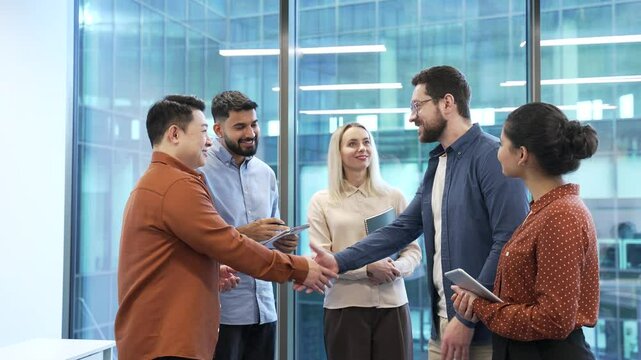 Business people shaking hands after deal at meeting while standing in modern office. Businessmen smile, suggesting successful collaboration, professional relationship and teamwork. Partners handshake