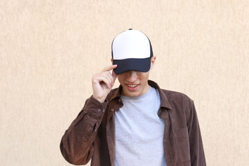 Smiling man in stylish baseball cap near beige wall. Mockup for design