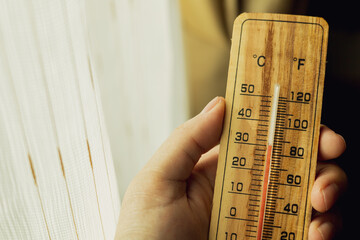 wooden thermometer A man's hand holds a device for measuring high air temperatures inside a...