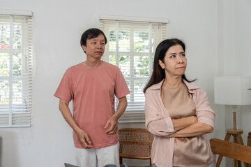 Middle-aged couple experiencing a tense moment indoors during a disagreement.