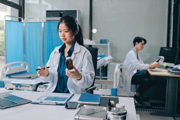 Positive doctor working on laptop in medical office, portrait.