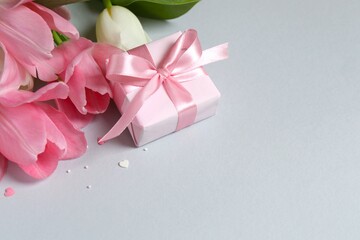 Beautiful fresh tulips with gift box on gray background