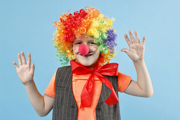Happy boy dressed like clown on light blue background. Surprise party