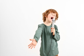 Little boy with microphone singing on white background