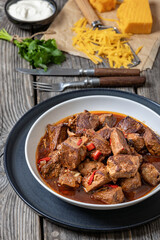 beef stew in a white bowl on rustic wooden table
