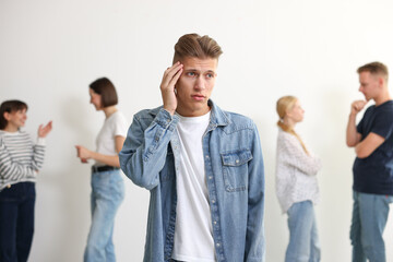 Young man feeling uncomfortable among people indoors, selective focus