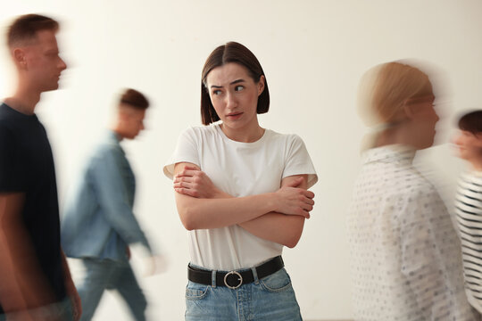 Young woman feeling uncomfortable among people indoors