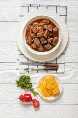 beef stew in a white bowl on rustic wooden table
