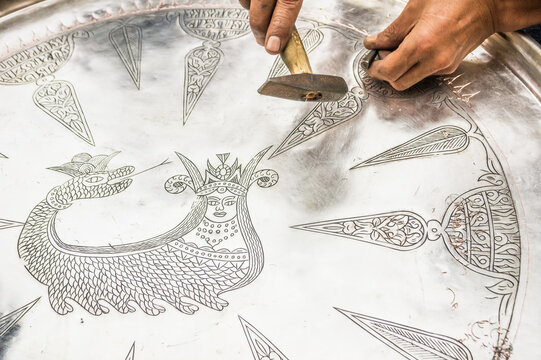 Artisan hands hammering traditional Shahmaran design onto a copper tray, authentic coppersmithing craft of Bakırcılık from Gaziantep, Turkey