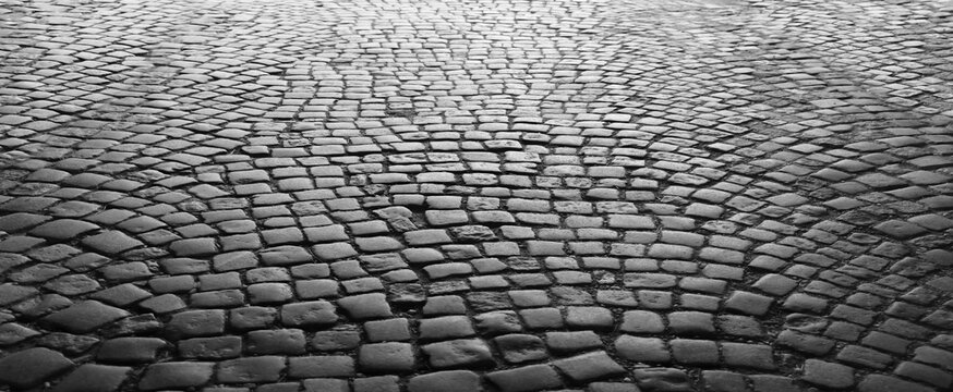 Old historical cobblestone pavement in perspective as background. vintage retro aged square cobble stone paving backdrop. Stone pavement texture. Abstract background of old cobbled stone pavement.