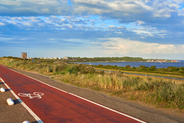 Bicycle path on dam in Holland. Yacht club and surf club at the lake (Grevelingermeer). Sunny summer evening, Cloudy sky for copy space. Netherlands, Zeeland, Brouwersdam.