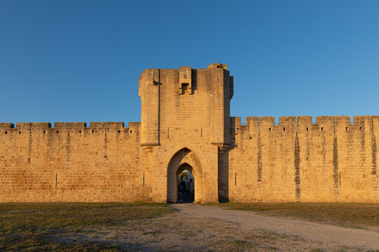 Sunrise over the Aigues-Mortes fortification, a historic gateway to the city in Southern France, Europe. A stunning view of the ancient walls and towers bathed in soft morning light