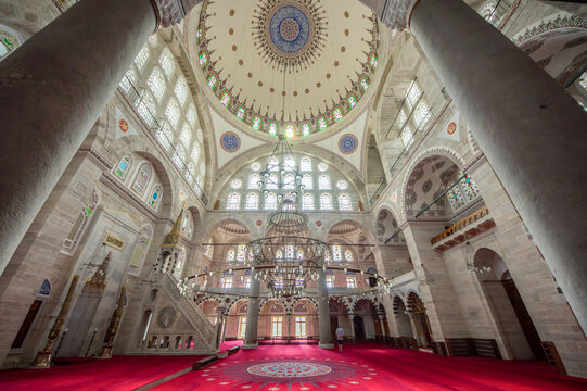 Interior view of the grand dome, columns, and minbar with red carpet inside the historic Suleymaniye Mosque, Istanbul, Turkey