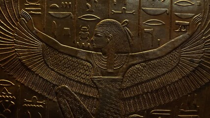 Isis wall carving on golden wall of tomb Macro view of goddess spread wings engraved on plate, ancient Egypt.