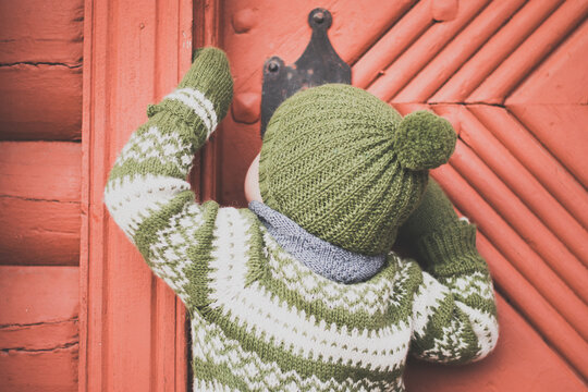 Boy peeking through keyhole in old norwegian stabbur door 