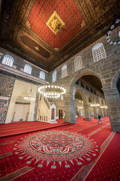 Interior of the historic Grand Mosque of Diyarbakir with red carpets, intricate wooden ceiling and white stone minbar pulpit, ancient architecture inside the great mosque or ulu camii in sur diyarbaki