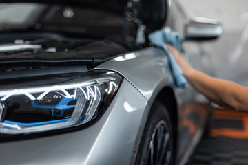 Car repair and wash in the service station. Detailing studio. Laser optics headlight. man wipes a car with a cloth