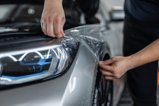 professional man does car detailing and covers it with protective film at a detailing service