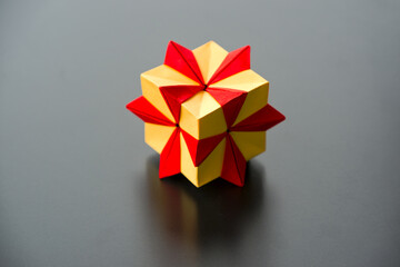 High angle view of red and yellow colored origami paper cube with spikes against black background. Photo taken February 15th, 2025, Zurich, Switzerland.