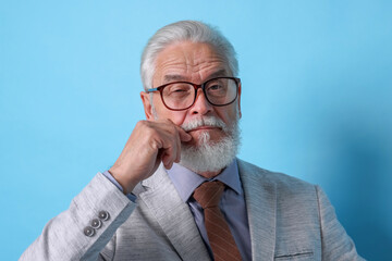 Portrait of serious senior man with silver beard on light blue background