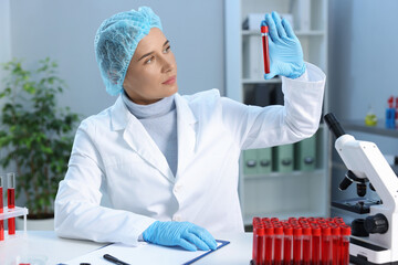 Laboratory testing. Doctor holding test tube with blood sample at table indoors