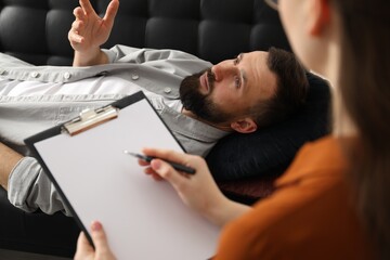 Psychologist working with patient during hypnosis session indoors, closeup