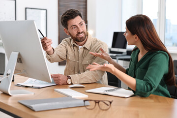 Colleagues working with computer at desk in office
