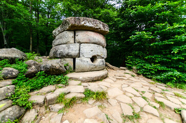 Ancient stone dolmen, nestled in verdant forest, bathed in soft, diffused light. Large stones...