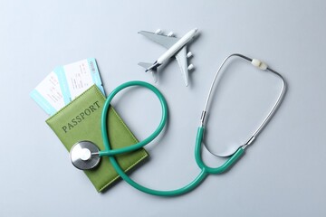 Medical tourism. Stethoscope, plane model, passport and flight tickets on light blue background,...