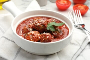 Delicious meatballs with tomato sauce, parmesan cheese and parsley served on white table, closeup