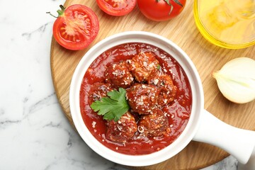 Delicious meatballs with tomato sauce, parmesan cheese and parsley served on white marble table, flat lay