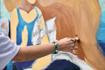 Female adult hand brings vibrant mural to life, showcasing creativity with brush strokes. Bright...