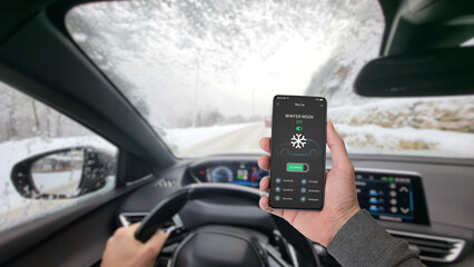 Driver activates winter mode via smartphone app while driving through a snowy landscape, optimizing fuel efficiency, traction, and vehicle heating for cold conditions