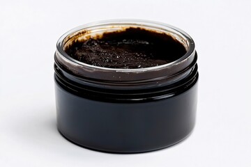Dark aromatic scrub in a clear jar on white background for skincare and spa treatments