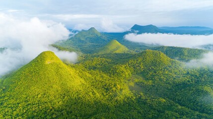 Fototapeta premium Aerial view of lush green mountains surrounded by misty clouds in tropical landscape