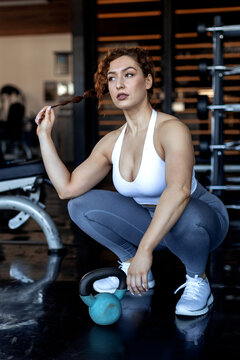 Young woman with courly hair exercise in gym with weights and worm up