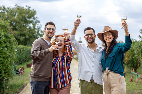 Group of friends with wine glasses on hands at vineyard