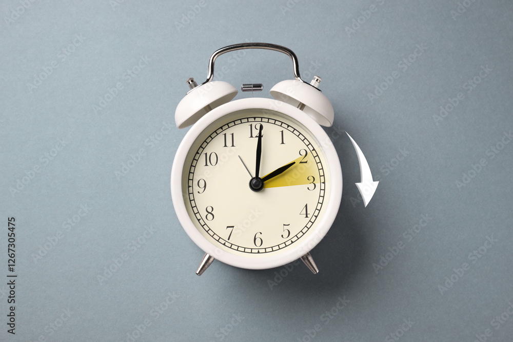 Poster Daylight saving time. White alarm clock on grey background, top view. Highlighted area and arrow showing time change by one hour forward