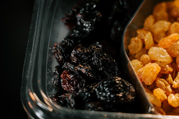 Dried raisins in a clear container showcasing dark and golden varieties