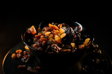 Dried raisins and mixed fruits in a dark bowl on a black background creating a rich visual appeal