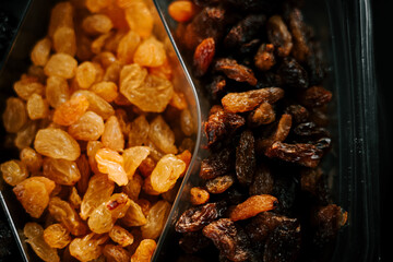 Raisins in a divided container showcasing golden and dark varieties, ideal for snacking or baking