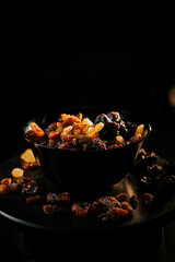 Delicious bowl of assorted raisins on a dark background highlighting their rich colors and textures