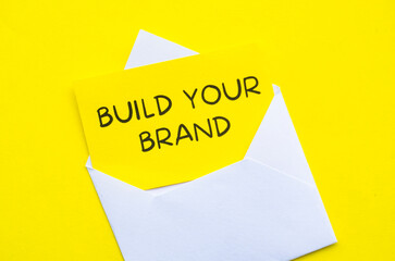 Build Your Brand text on yellow notepad in a white envelope. Business and Branding concept